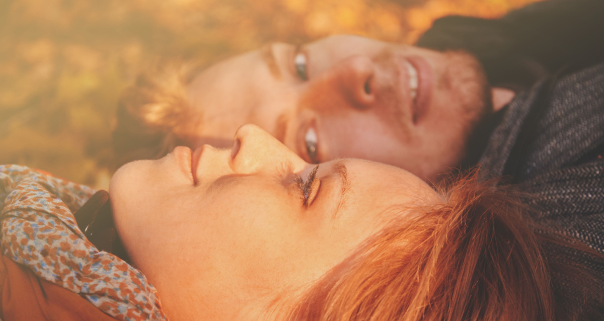man looking lovingly at woman lying on the grass