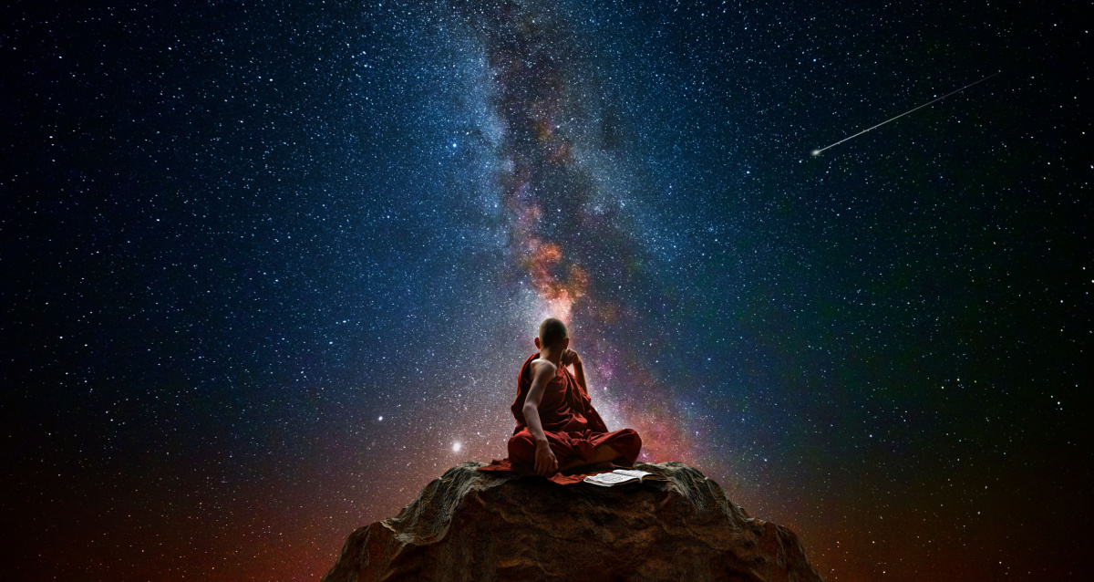 monk sitting on top of a mountain with a starry sky