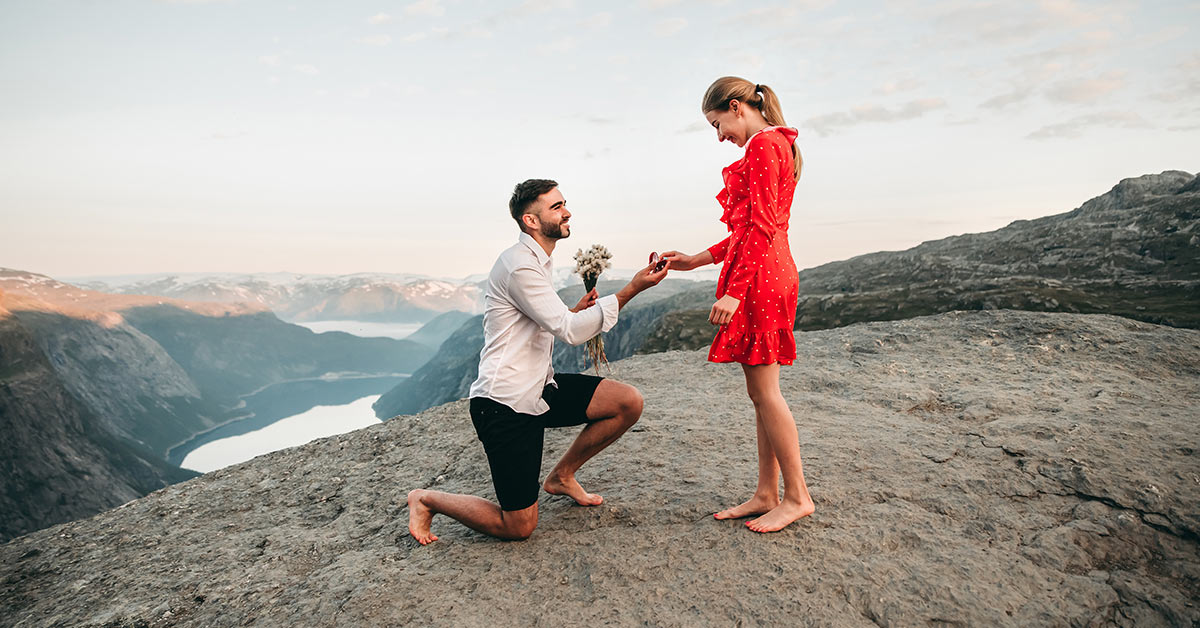 man proposing to woman in red dress