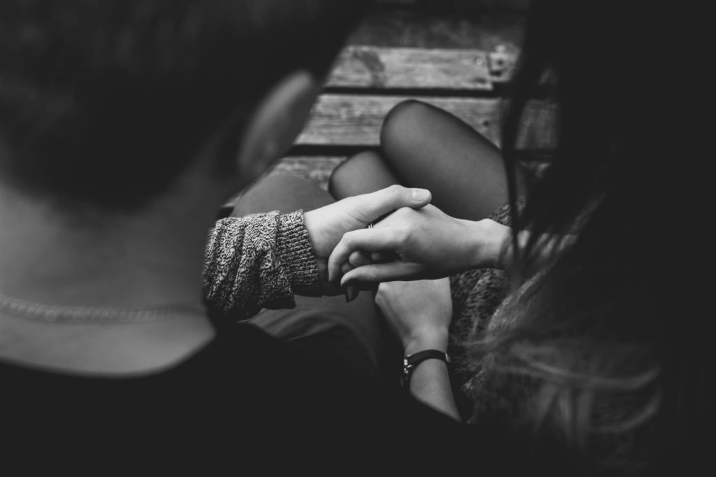 A black and white image of man holding a woman's hand.