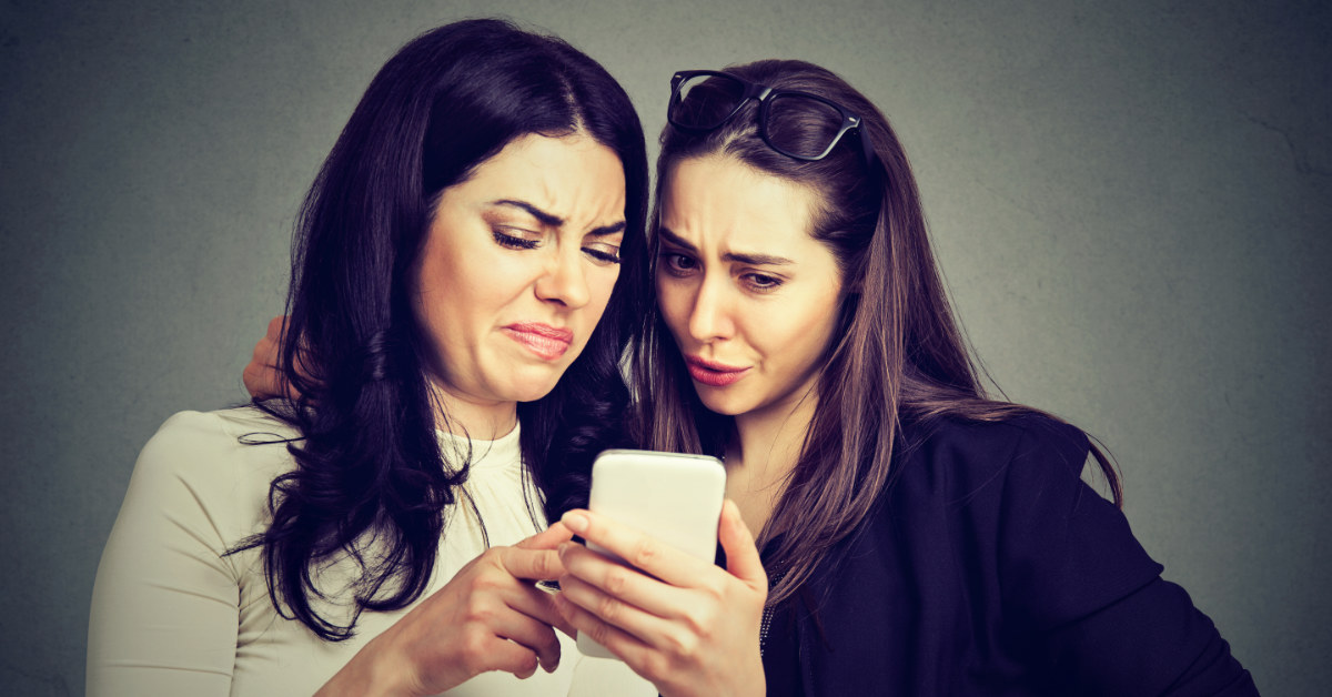 two women negatively reacting to something they see on their phone