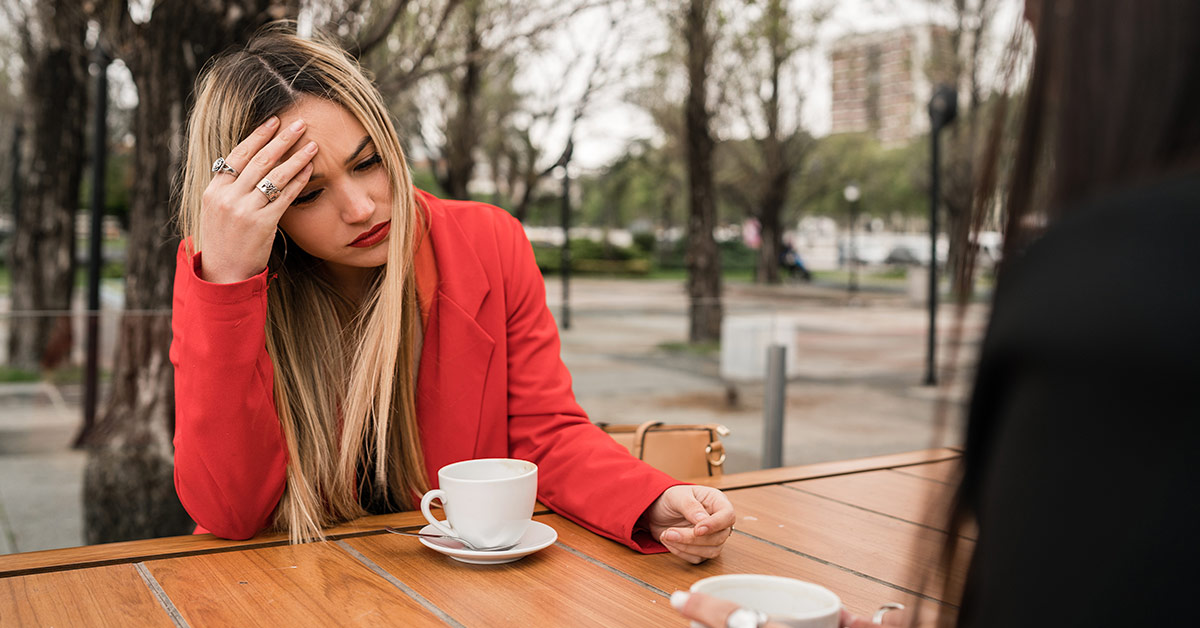 distressed woman sitting at a table drinking coffee