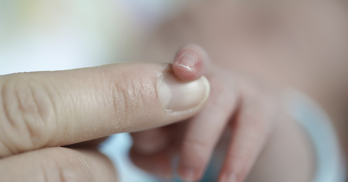 infant holding a parent's finger