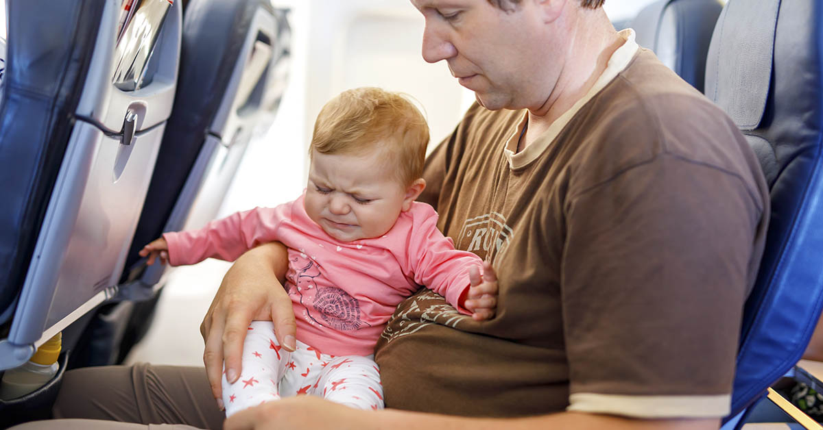 baby sitting on mans lap during flight