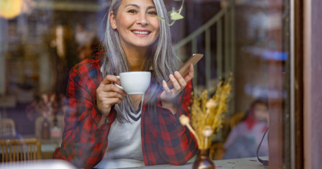Gray haired woman drinking coffee at a cafe