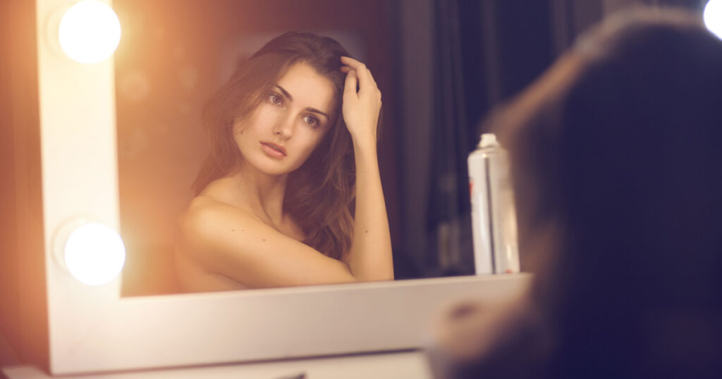 young woman with Narcissism looking into a mirror at herself

