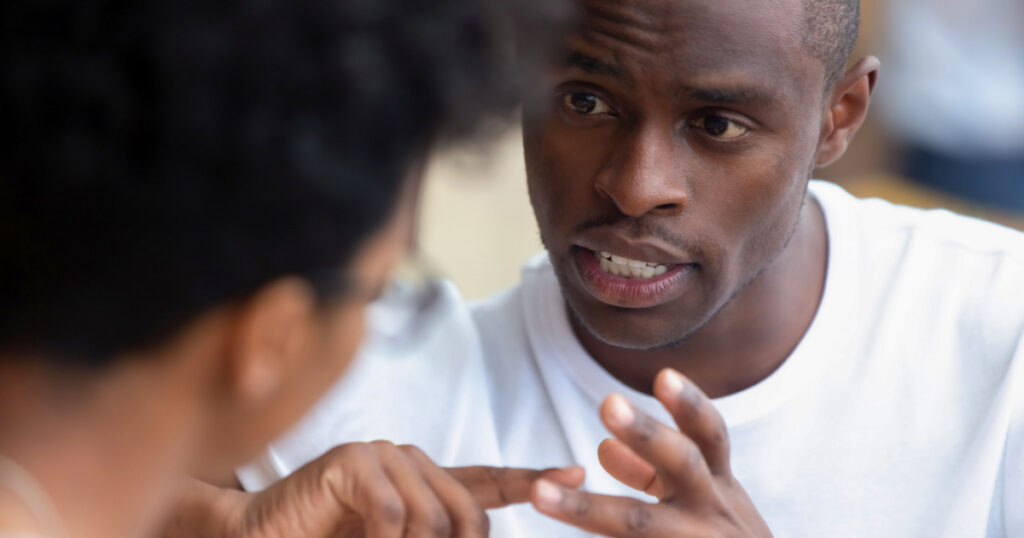 Focused african american man looking speaking to woman having business talk negotiating explaining, serious black guy having conversation with girlfriend friend discussing important issues at meeting