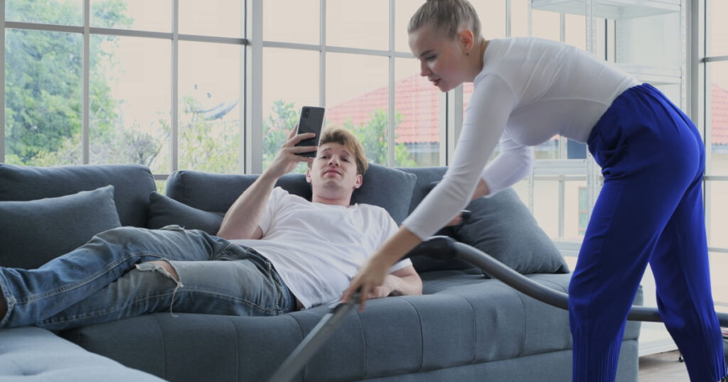 lazy man with narcissism  on couch while girlfriend cleans