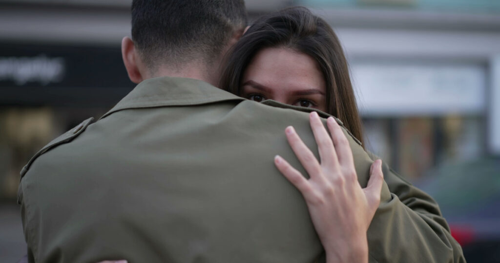 Couple embrace standing in street in empathic hug. Caring and understanding concept during hard times. Young man and woman hug