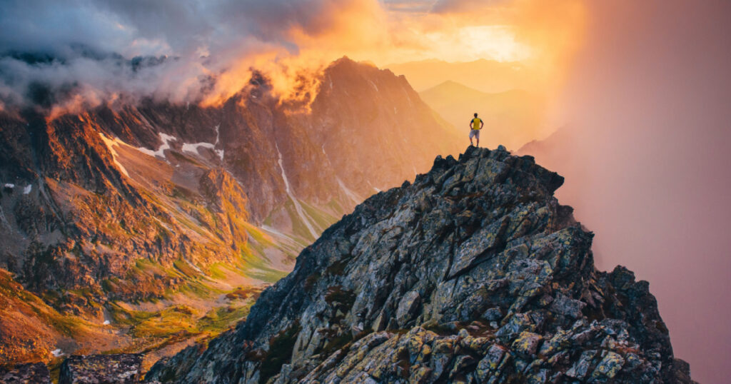 Man on the top of the hill watching wonderful scenery in mountains during summer colorful sunset in High Tatras in Slovakia
