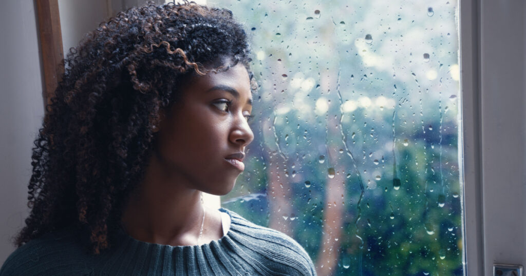 Black woman feeling depression symptoms alone at home
