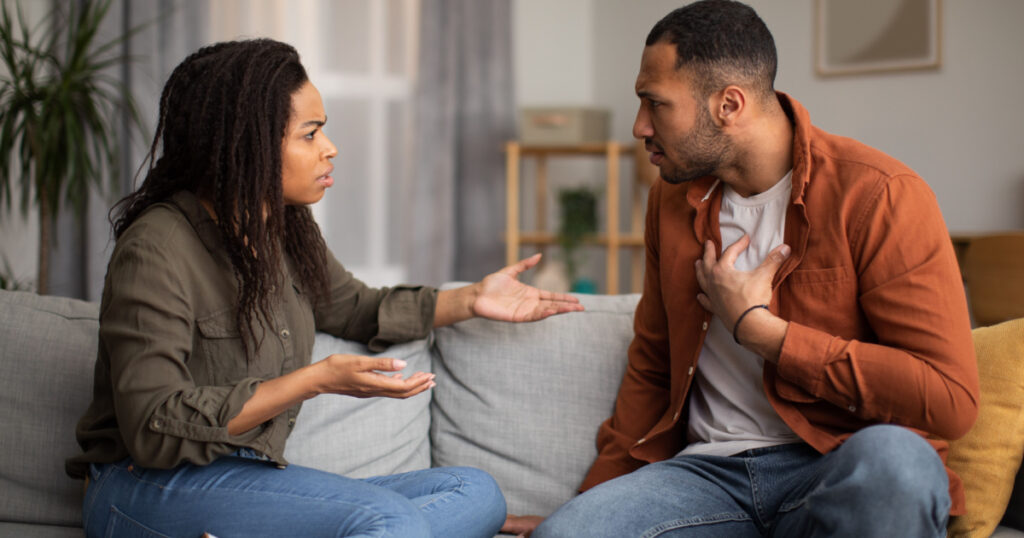 Angry Black Couple Having Quarrel Experiencing Crisis In Relationship Sitting On Sofa At Home. Spouses Having Conflict Breaking Up. Marital Problems, Divorce Concept