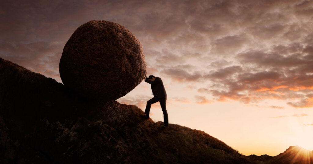 Business concept, Young businessman pushing large stone uphill with copy space
