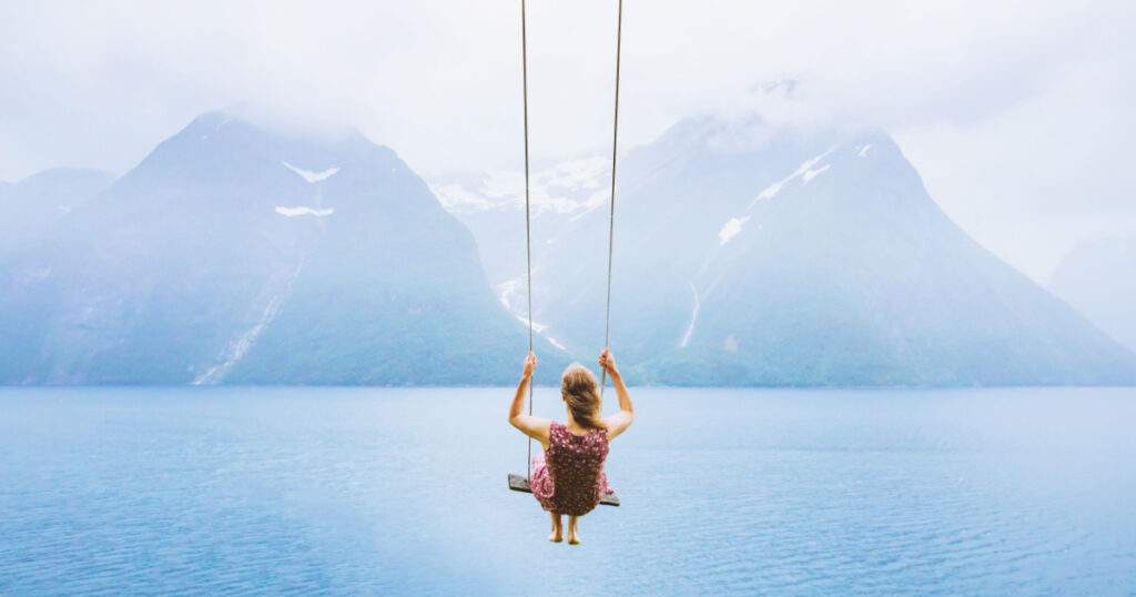 dream concept, beautiful young woman on the swing in fjord Norway, inspiring landscape
