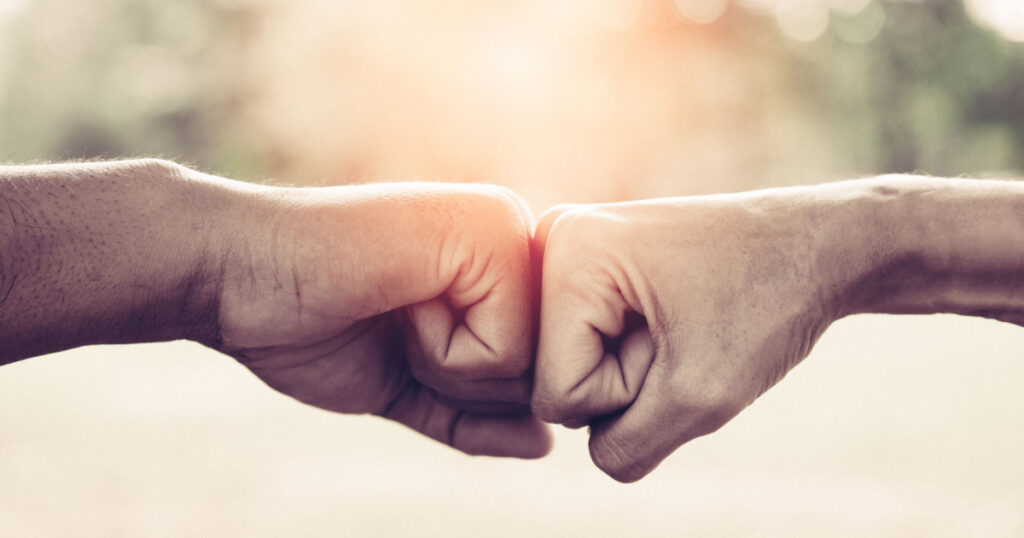 A close up image of a fist bump in vintage tone. Hands of young people show strength teamwork in the nature, team concept.
