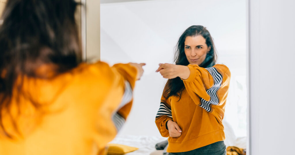 woman pointing at self in mirror
