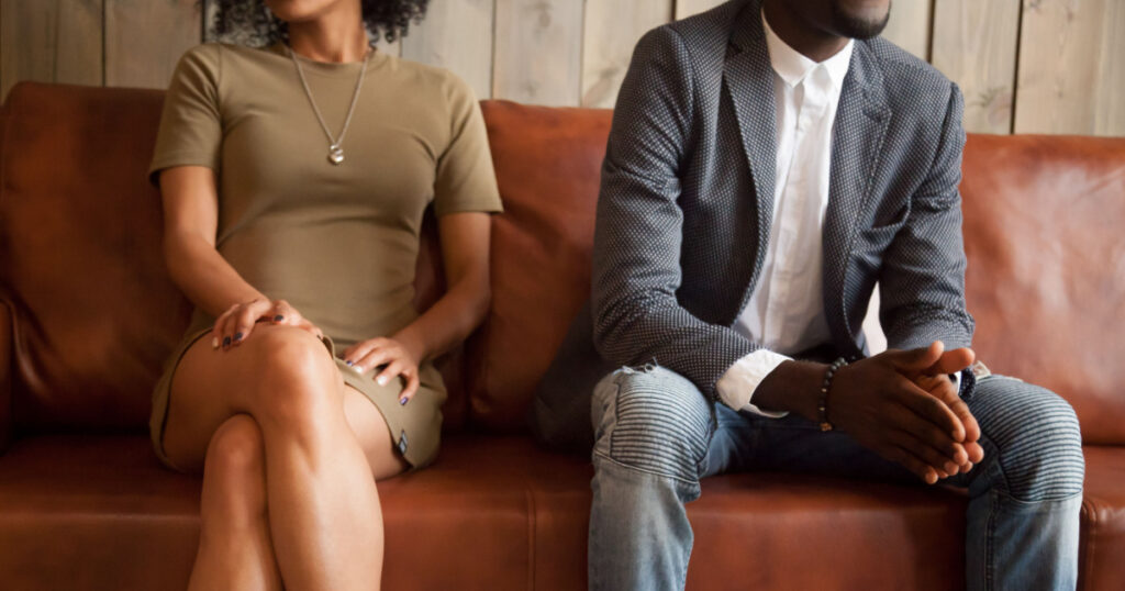 African american unhappy couple sitting on couch after quarrel fight thinking of break up or divorce, black upset man and woman not talking having conflict, bad relationships concept, close up view
