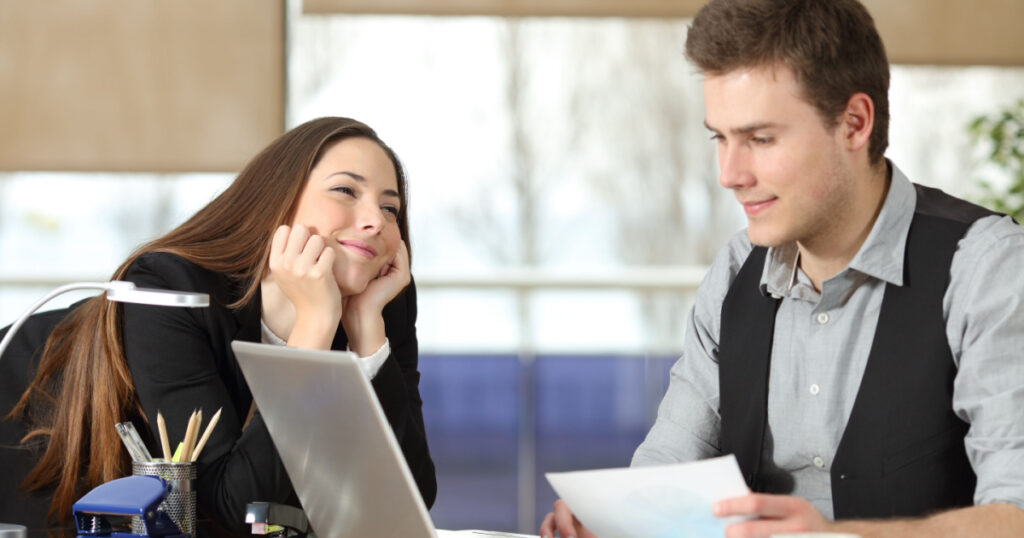 Candid young businesswoman falling in love with a colleague at office
