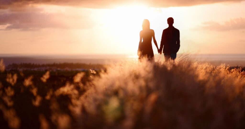 Young couple enjoying the sunset in the meadow
