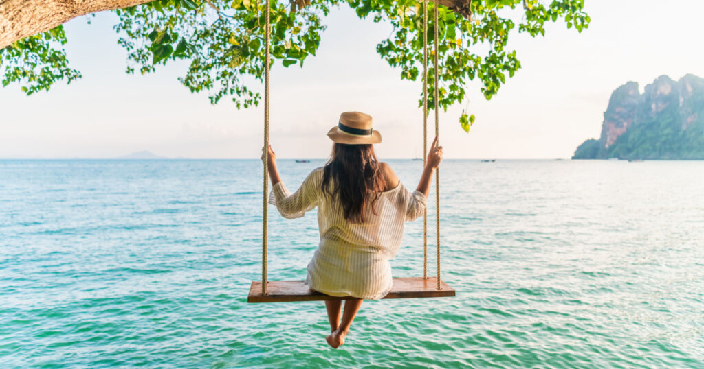 Traveler woman relaxing on swing above Andaman sea Railay beach Krabi, Leisure tourist travel Phuket Thailand summer holiday vacation trip, Beautiful destinations place Asia, Happy dream concept
