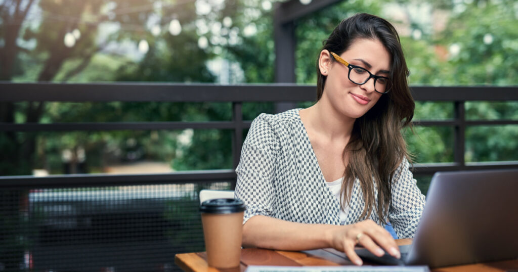 Being productive outside of the office. Cropped shot of an attractive young businesswoman working on her laptop while sitting outdoors at a cafe.
