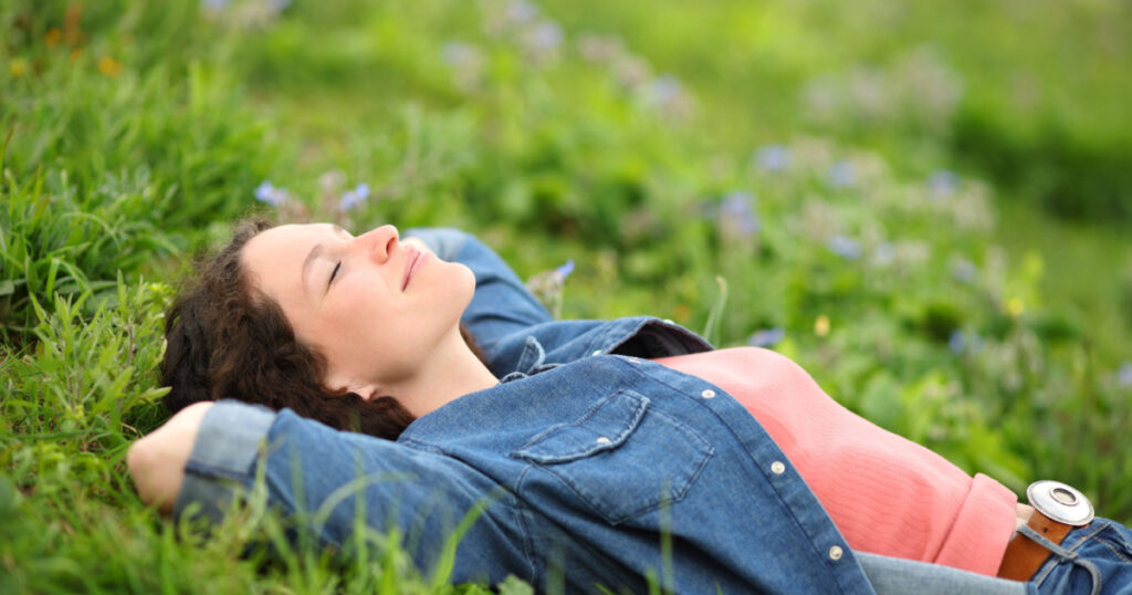 Beautiful woman resting and relaxing lying on the grass in a park
