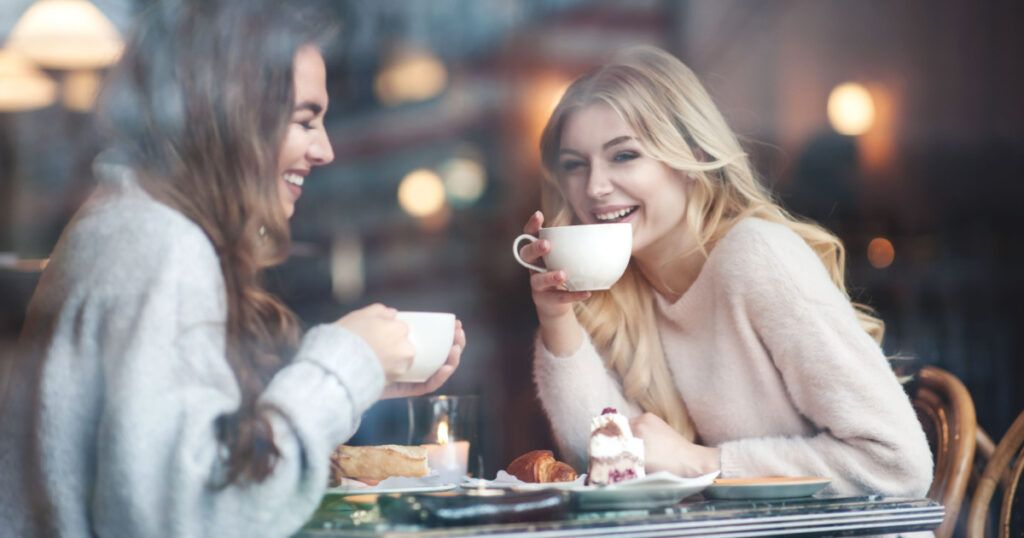 Two girl friends drinking coffee in the cafe
