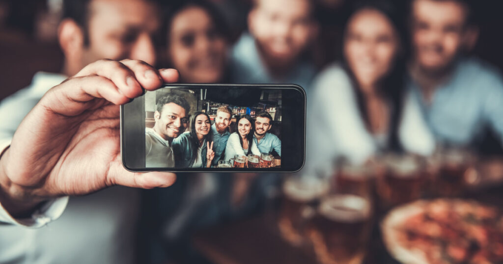 Selfie time! Handsome friends making selfie and smiling while resting at pub.
