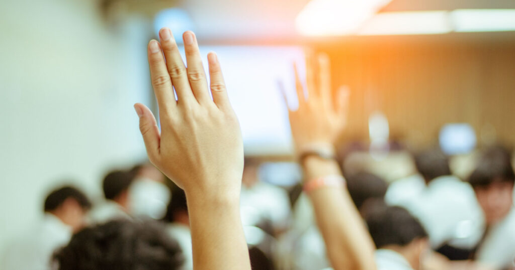 businessman raising hand during seminar. Businessman Raising Hand Up at a Conference to answer a question.
