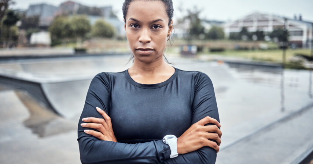 Fitness, sports and portrait of a woman in the city for an outdoor run, exercise or training. Serious, motivation and young female athlete or runner with crossed arms after a cardio workout outside.
