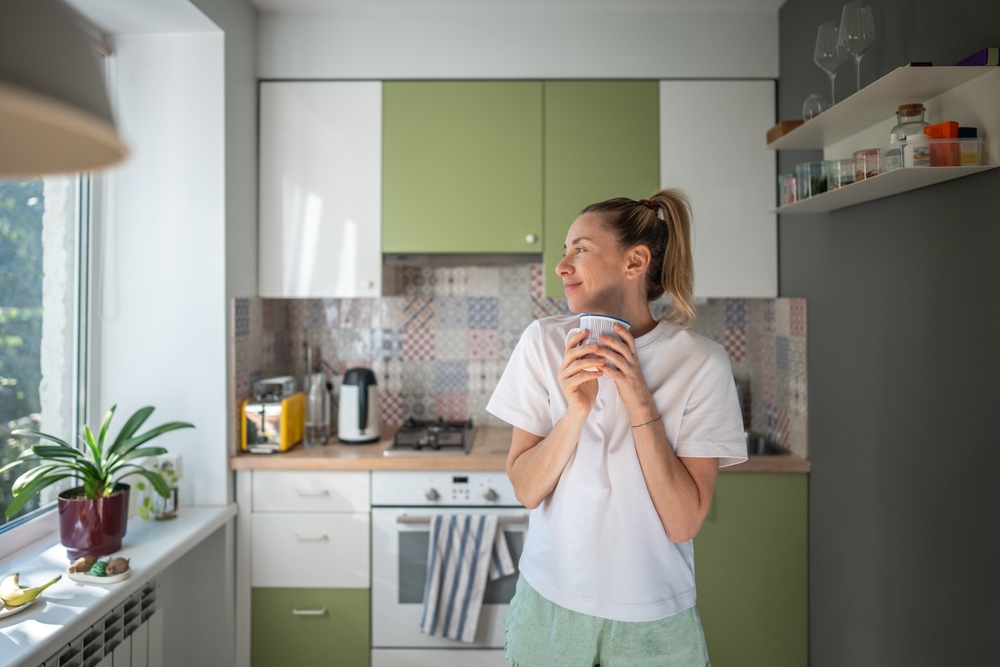happy smiling woman in kitchen holding cup
