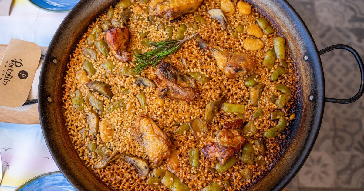 Authentic Valencia paella in a pan with chicken, vegetables, and rosemary. Top view.