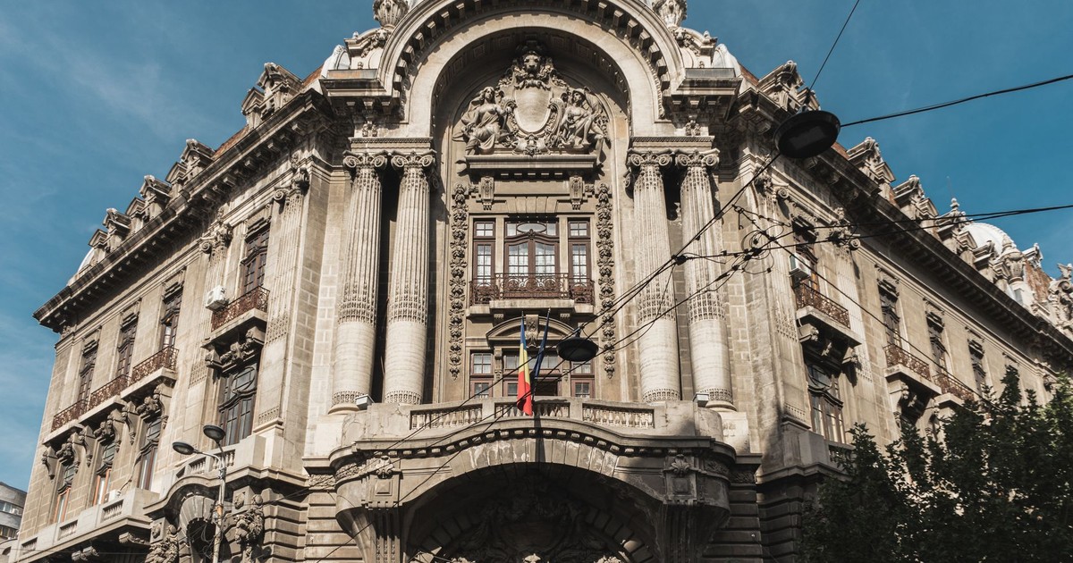 Captivating architecture of a historic building in Bucharest, showcasing classical details under a clear blue sky.