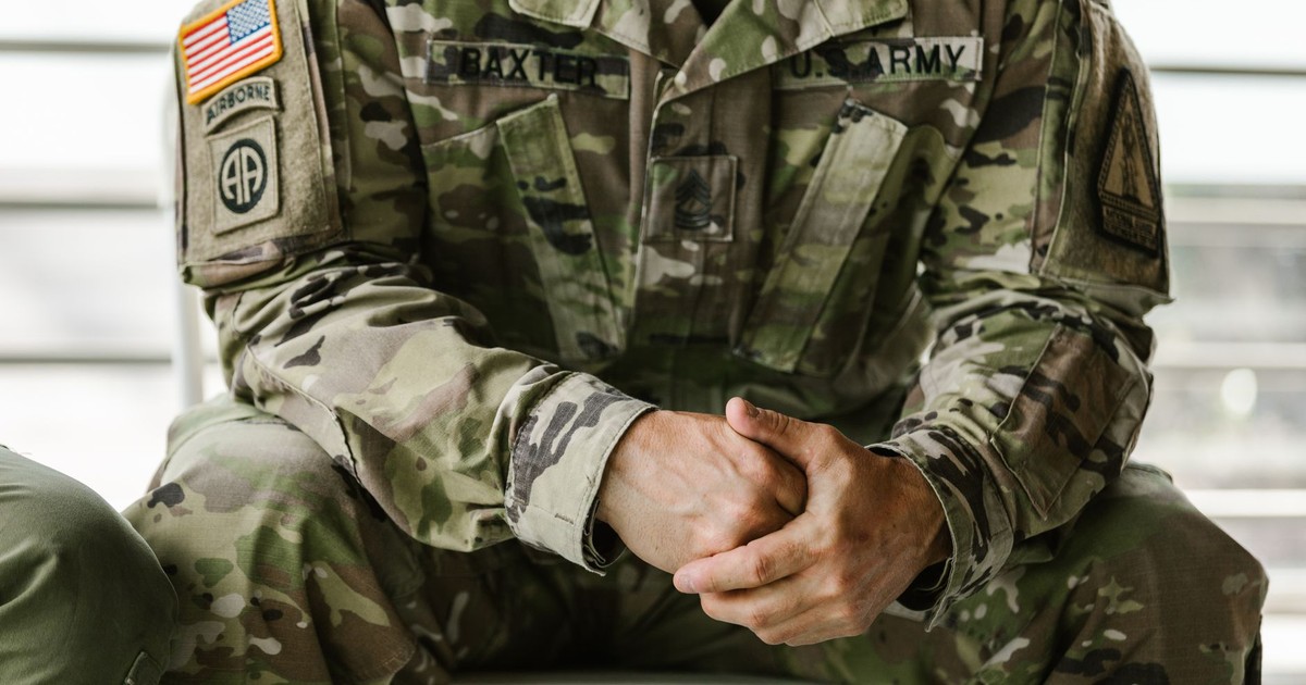 Close-up image of a soldier wearing a camouflage military uniform, displaying patches and insignia.