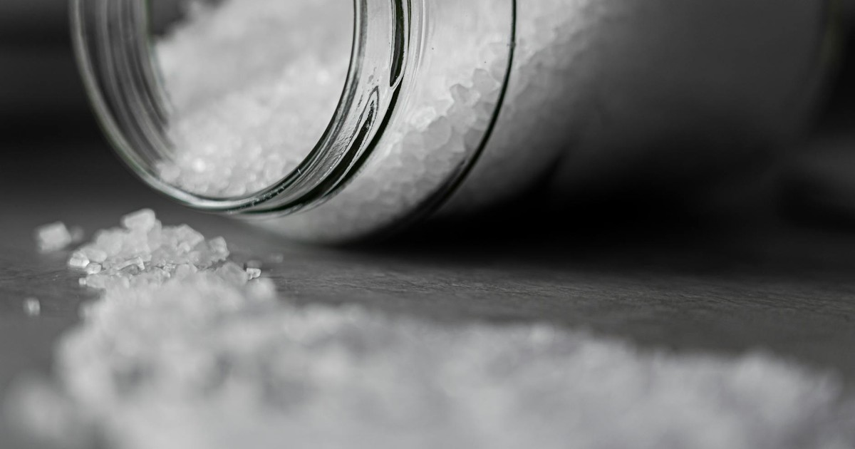Detailed image of rock salt pouring out from a glass jar with a selective focus effect.