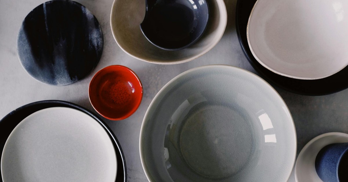 A collection of various colored ceramic bowls and plates, artistically arranged on a flat surface.