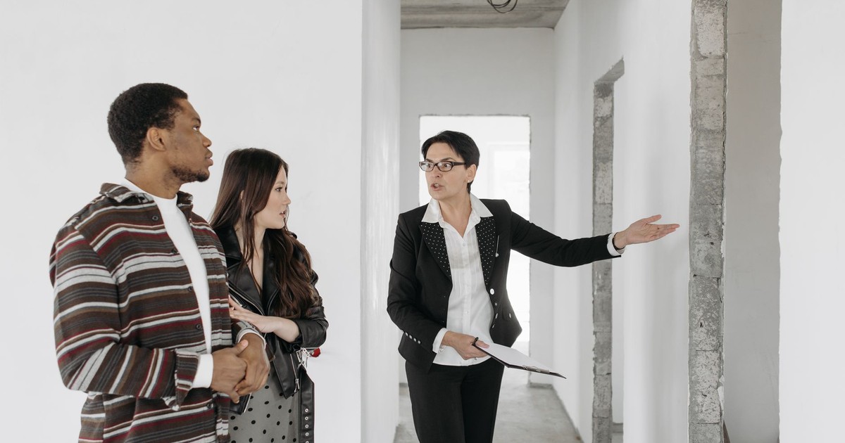 Real estate agent shows a house to a couple, discussing features.