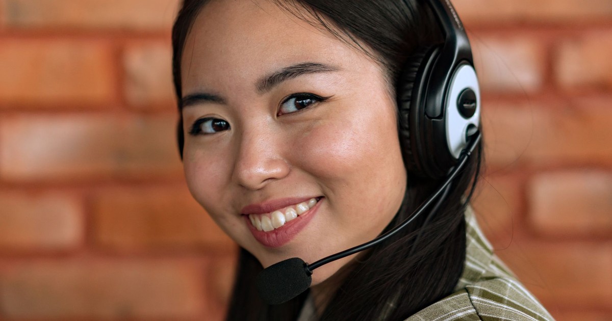 Close-up of a young Asian woman wearing headphones and smiling, indoors.