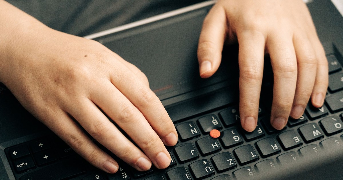 Close-up of hands typing on a black laptop's keyboard emphasizing productivity.