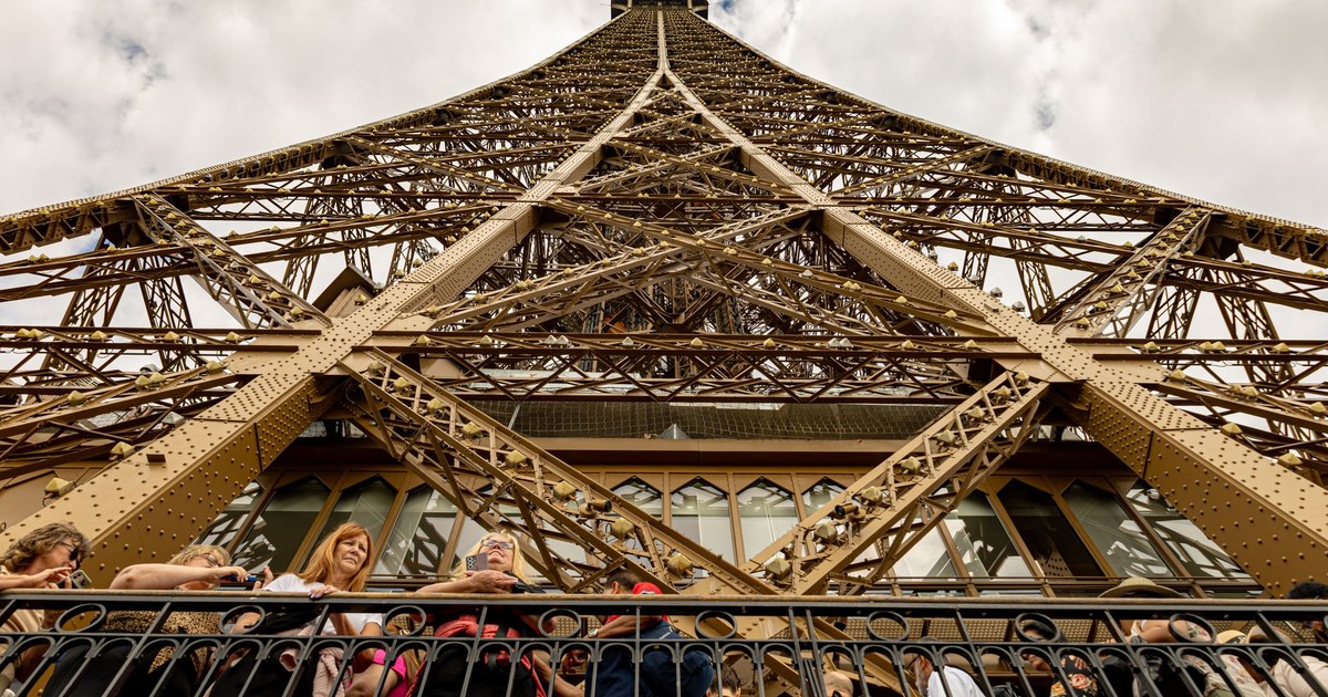 Tourists gather at the Eiffel Tower base, showcasing iconic architecture and a vibrant crowd.