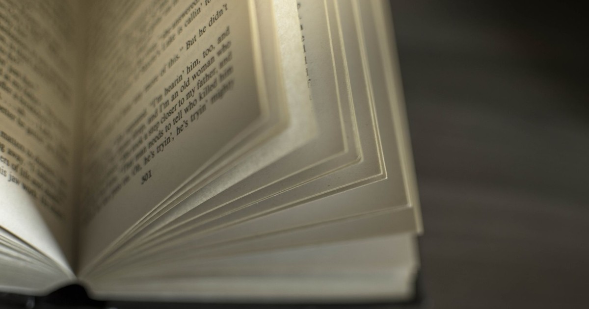 A close-up image of an open book with visible text, showcasing turning pages.