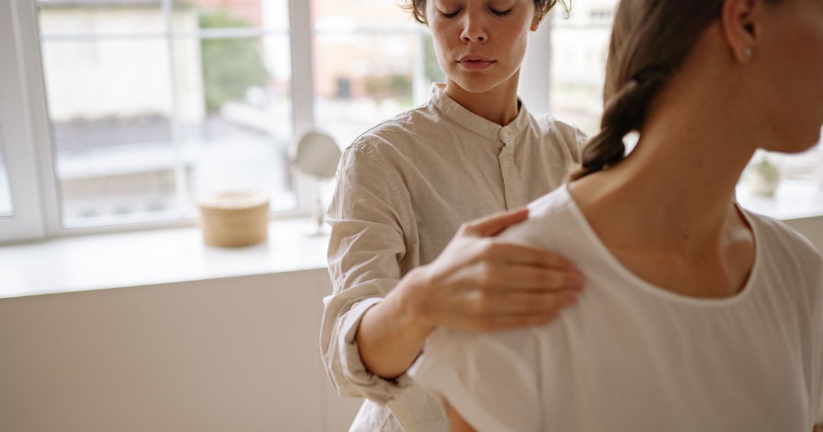 A physiotherapist provides treatment to a client in a bright, modern clinic setting.