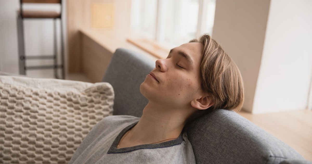 Young man relaxing on a comfortable sofa at home, enjoying a peaceful moment indoors.