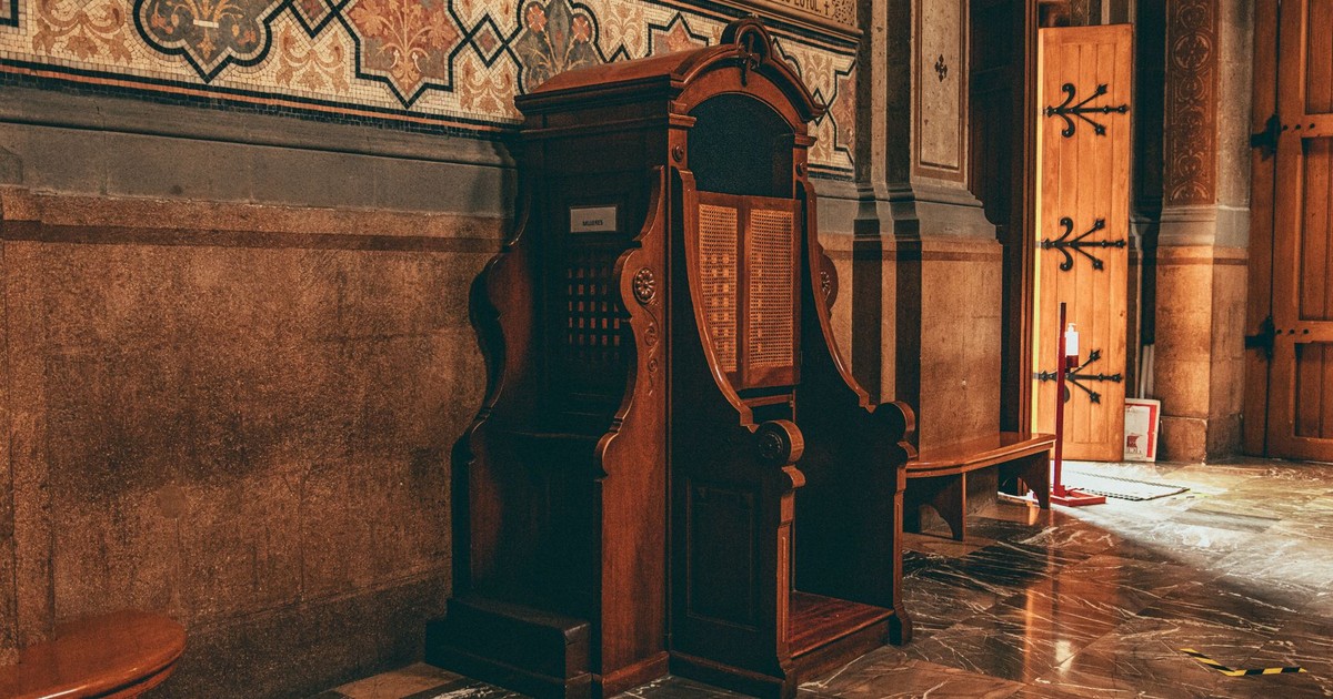 A beautifully decorated church interior in Ciudad de México featuring a wooden confessional booth and intricate wall designs.