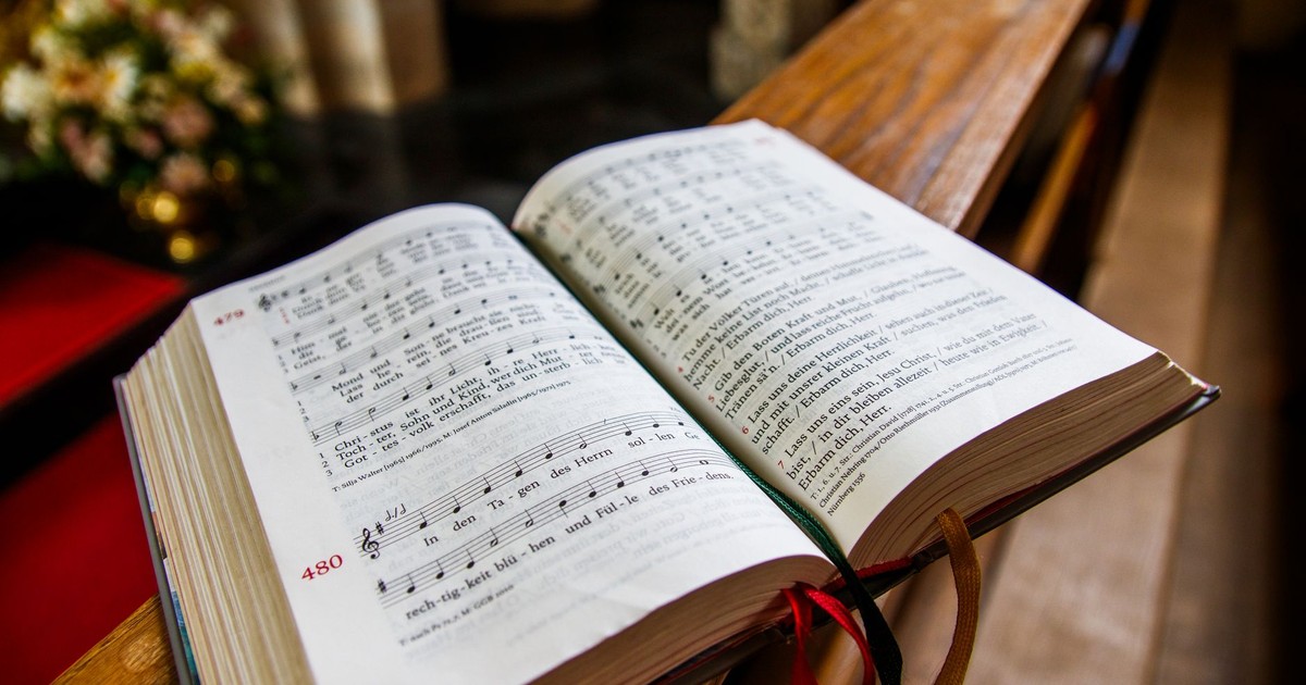 A music hymn book opened on a church pulpit, illuminated by warm indoor lighting.
