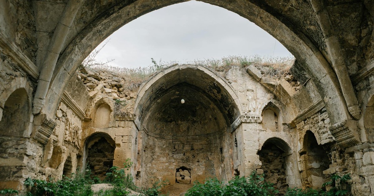 Explore the ancient stone arches and overgrown ruins of a historical abandoned structure.