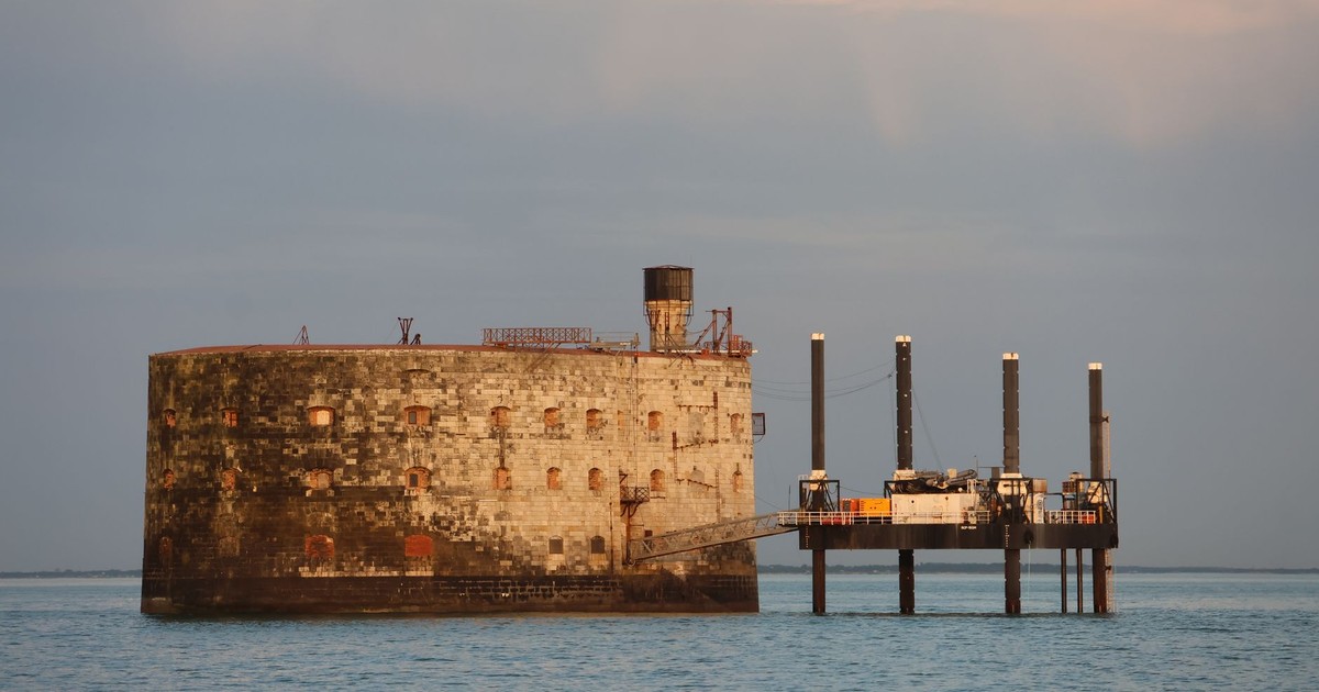 Stunning view of a historic fortification surrounded by tranquil sea water at sunset.