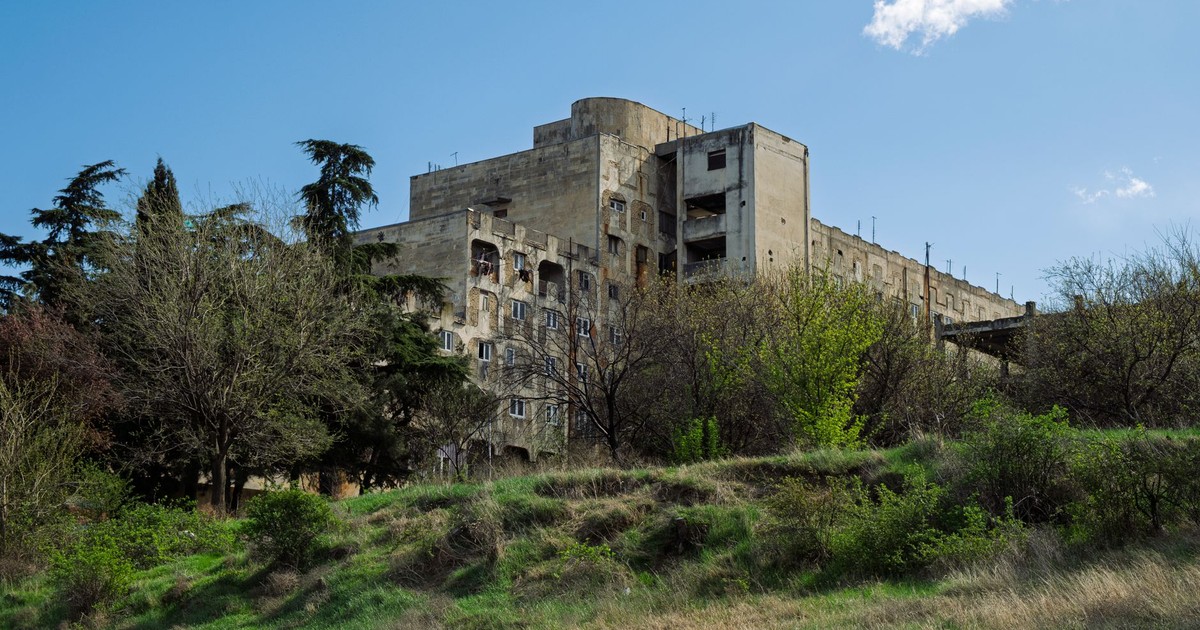 Abandoned Soviet-era building surrounded by spring foliage in Tbilisi, Georgia.