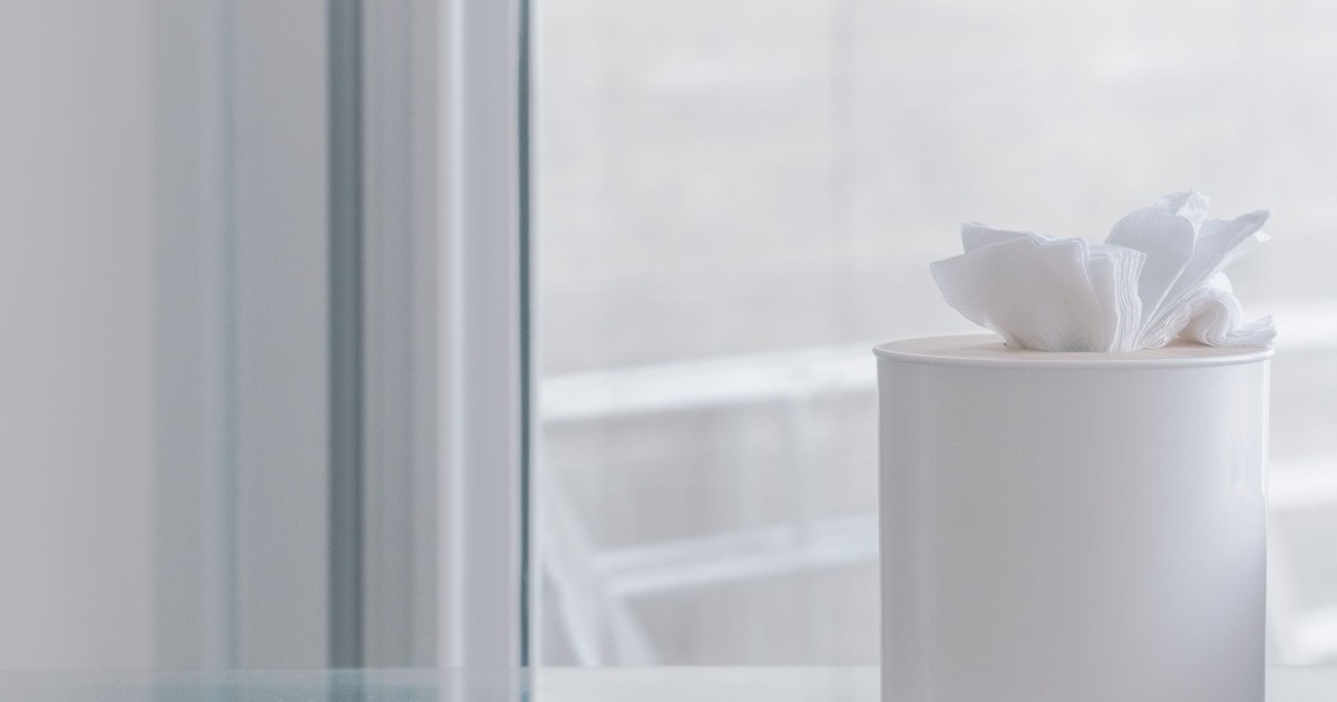 Elegant white tissue container on glass surface, evoking simplicity and minimalism.
