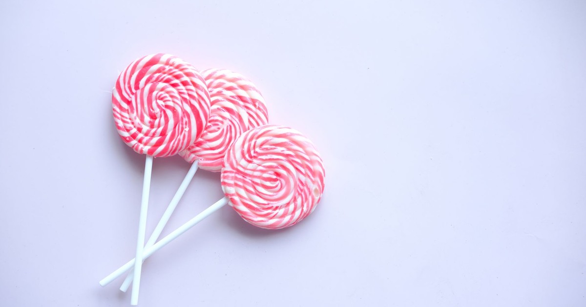 A delightful close-up of three pink swirl lollipops on a white surface, perfect for candy-themed projects.